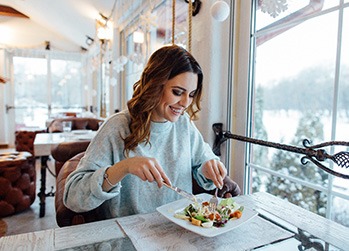 Woman smiling while eating salad at restaurant