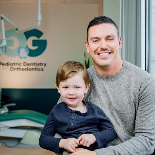 Pediatric dentist and young dental patient smiling together