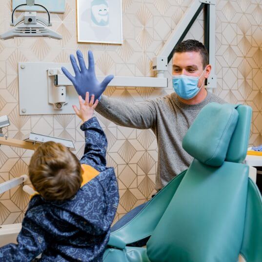 Child giving pediatric dentist a high five