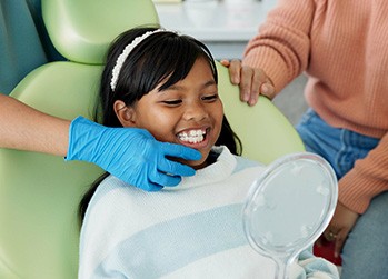 Child smiling at reflection in handheld mirror