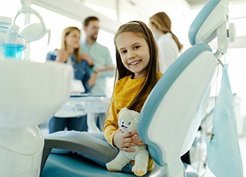 Child smiling while sitting in treatment chair
