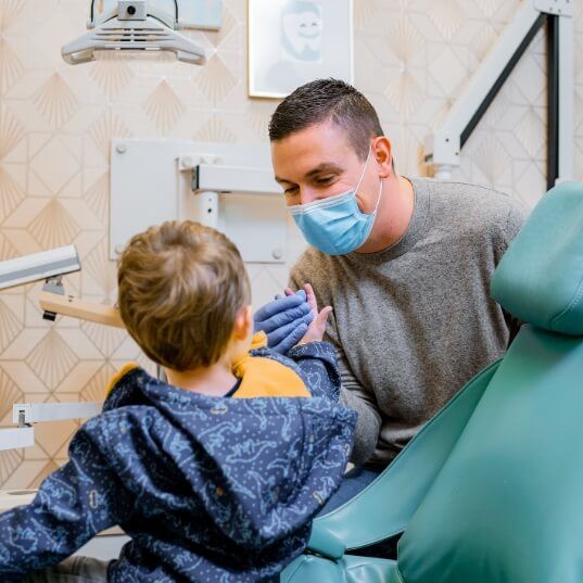 Pediatric dentist talking to child during emergency kid's dentistry visit