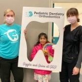 Two pediatric dental team members and young patient smiling together
