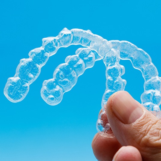 closeup of person holding two clear aligners 