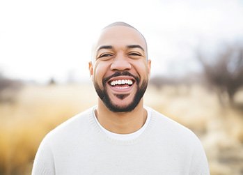 Man in white shirt smiling outside