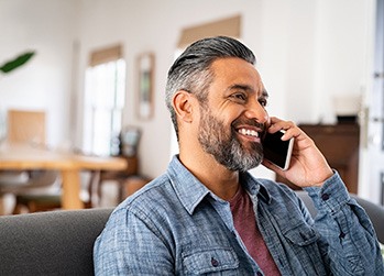 Man in blue shirt smiling while talking on phone