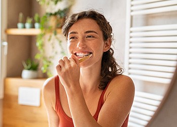 Woman smiling while brushing her teeth
