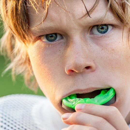 Teen placing a green athletic mouthguard