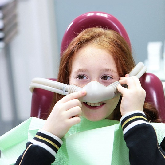 Girl with red hair in dental chair with nitrous oxide mask over nose