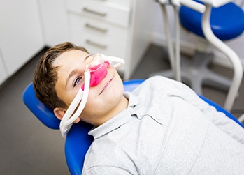 Boy in dental chair with pink nitrous oxide mask over nose