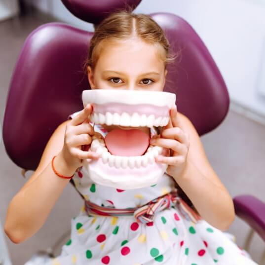 Child holding model smile during early orthodontic intervention
