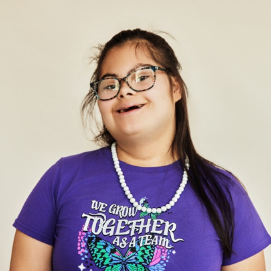 Child with glasses and Down Syndrome smiling 