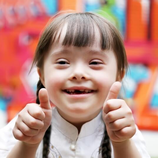 Child giving two thumbs up after special needs dentistry visit