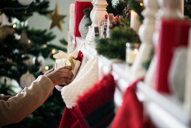 person putting wrapped Christmas gift in stocking