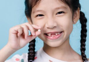 Child holding pulled tooth. 