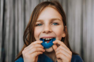 a child smiling and holding their mouthguard 